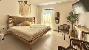 A bedroom with a bed, a desk, a chair, a TV, and a window with curtains. - Mr. W : Cozy Urban Stay : Explore Guadalajara (Guadalajara)
