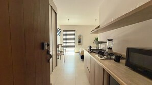 A modern kitchen with a wooden door, a countertop with a blender, a TV, and a plant. - Mr. W : Cozy Urban Stay : Explore Guadalajara (Guadalajara)