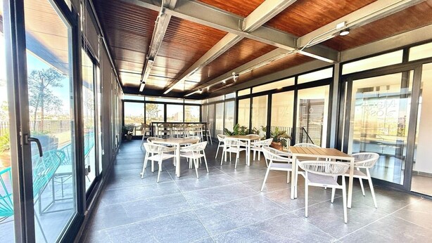 A spacious indoor area with large windows, a high ceiling with wooden beams, and multiple seating arrangements. - Mr. W : Cozy Urban Stay : Explore Guadalajara (Guadalajara)
