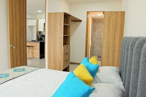 A bedroom with a bed, pillows, a wardrobe, and a bathroom visible through an open door. - Stylish 1BR Apartment in Mosaicos Tlaquepaque (Tlaquepaque)