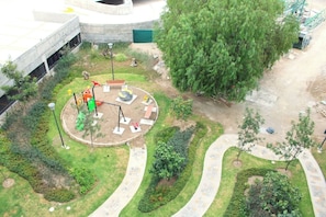 A playground with swings and slides, surrounded by landscaped gardens and a paved walkway. - Stylish 1BR Apartment in Mosaicos Tlaquepaque (Tlaquepaque)