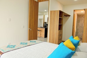 Ein Schlafzimmer mit einem Bett, einem Kleiderschrank und einem durchgehenden Tür angedeuteten Badezimmer.