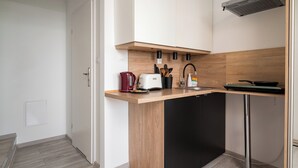 A modern kitchen with a wooden countertop, black cabinets, a built-in dishwasher, and a stainless steel range hood. - Praga-Południe Chic Studio (Warszawa)