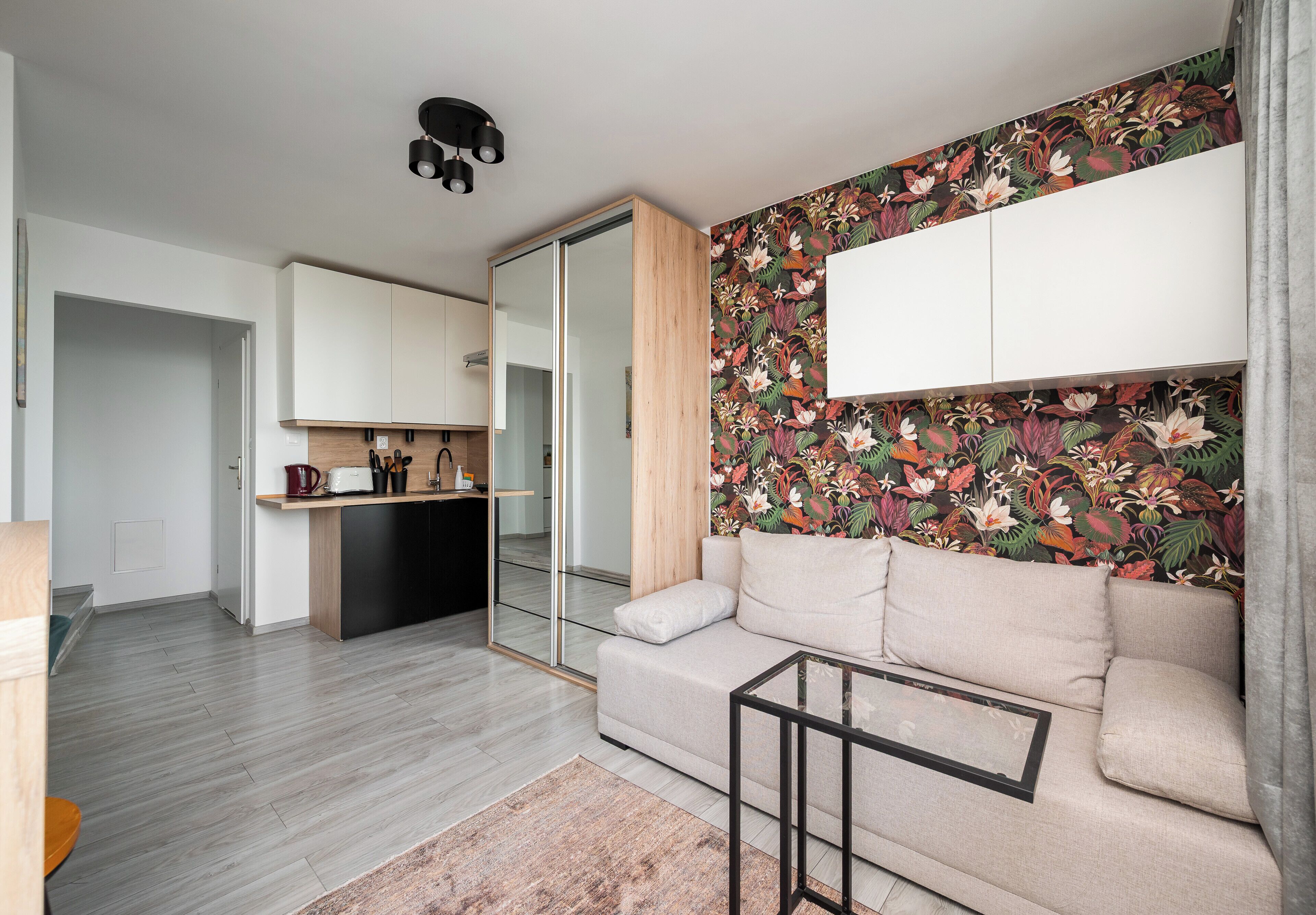 A modern living room with a sofa, a coffee table, and a kitchen area with cabinets and a countertop.