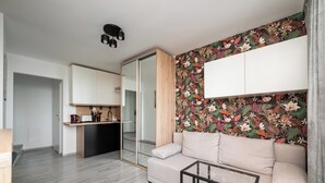 A modern living room with a sofa, a coffee table, and a kitchen area with cabinets and a countertop. - Praga-Południe Chic Studio (Warszawa)