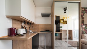 A modern kitchen with a wooden countertop, a red kettle, a white toaster, and a small island with a sink. - Praga-Południe Chic Studio (Warszawa)