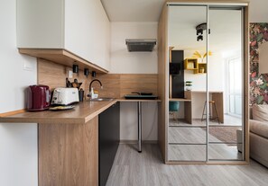 Eine moderne Küche mit einer Holzauskładung, einem roten Wasserkocher, einem weißen Toaster und einer kleinen Kücheninsel mit Spüle.