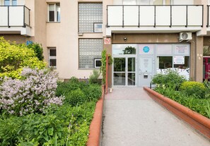 Ein Gebäudeeingang mit Glastür, einem Schild und einem kleinen Garten.