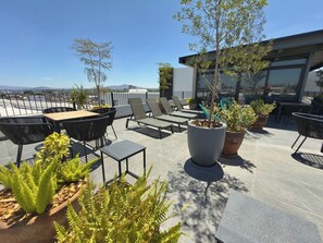 A rooftop terrace with outdoor seating, potted plants, and a view of the cityscape. - Mr. W | Beautiful Apartment Close to Downtown GDL (Guadalajara)