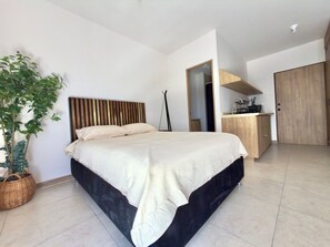 A modern bedroom with a bed, a wooden headboard, a potted plant, a desk, and a wardrobe. - Mr. W | Beautiful Apartment Close to Downtown GDL (Guadalajara)