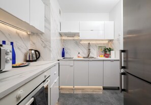 Eine moderne Küche mit weißen Schränken, einem Edelstahl-Kühlschrank und einer Marmor-Spritzschutzwand.