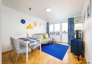 Een moderne woonkamer met een eettafel, bank en een blauw vloerkleed.