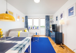 Een moderne kamer met een bed, een eettafel, een televisie en uitzicht op de stad.