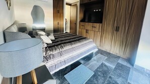 Une chambre moderne avec un lit, une télévision et une armoire.