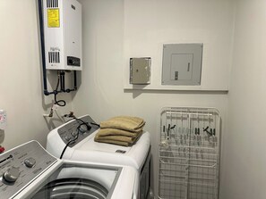 A laundry room with a washing machine, a dryer, and a utility room with a thermostat and electrical panel. - Stylish 2BR Apartment at Torre Bermeo (Zapopan)