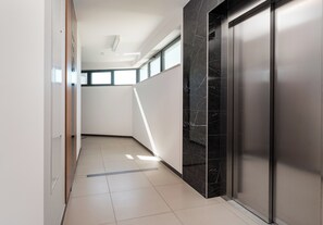 A modern hallway with a marble wall, a door, and a window allowing natural light. - Warszawa Rakowska Smart Studio (Warszawa)