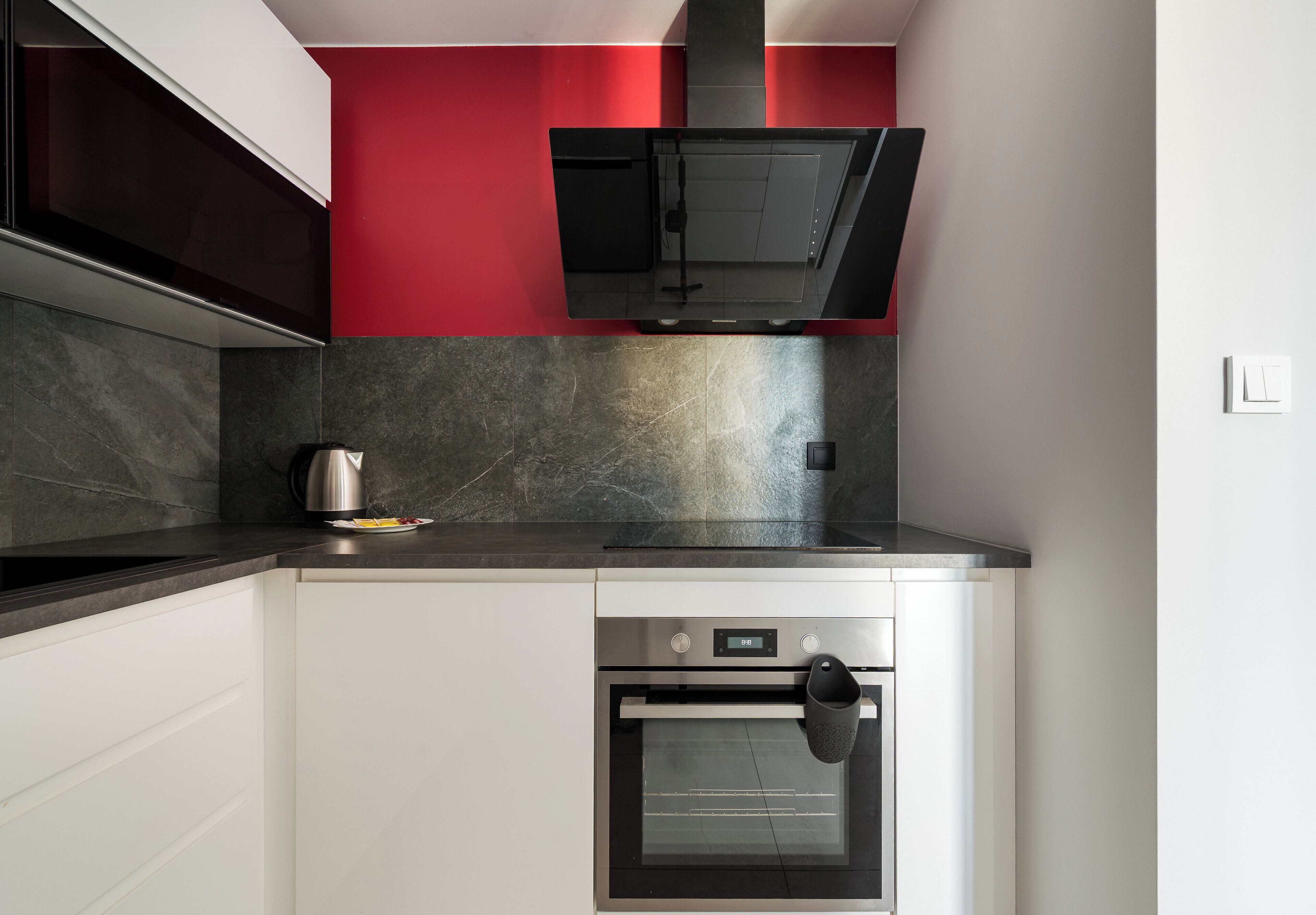 A compact kitchen with a built-in oven, a kettle, and a microwave.