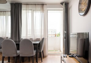 Ein Essbereich mit Tisch und Stühlen, einem Fernseher und einem Balkon mit Blick.