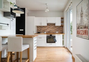 Een moderne keuken met witte kastjes, een tegelwand en een houten aanrecht.