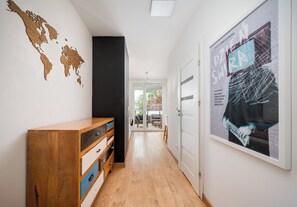 Un couloir avec une armoire en bois, une fresque représentant une carte du monde et une affiche encadrée accrochée au mur.