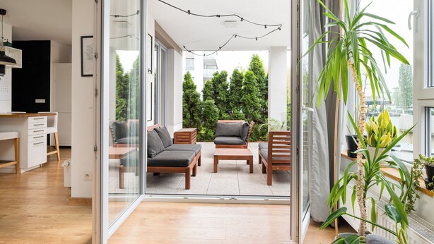 Ein moderner Wohnraum mit Glastür zu einem Außenbereich, Holzmöbeln und einem Blumentopf.