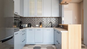 Una cocina moderna con armarios azul claro, un refrigerador de acero inoxidable, salpicadero con patrón hexagonal y encimera de madera.