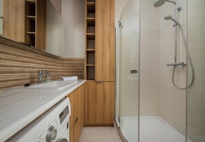 Ein modernes Badezimmer mit einem Holzkosmetikschrank, einer Glasdusche und einer integrierten Ablage.
