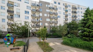 Un edificio residencial de varios pisos con balcones, un patio de juegos y áreas ajardinadas.