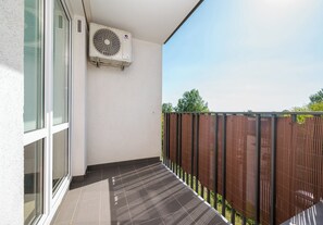 Ein Balkon mit Glastür, brauner Umzäunung und Klimaanlage.