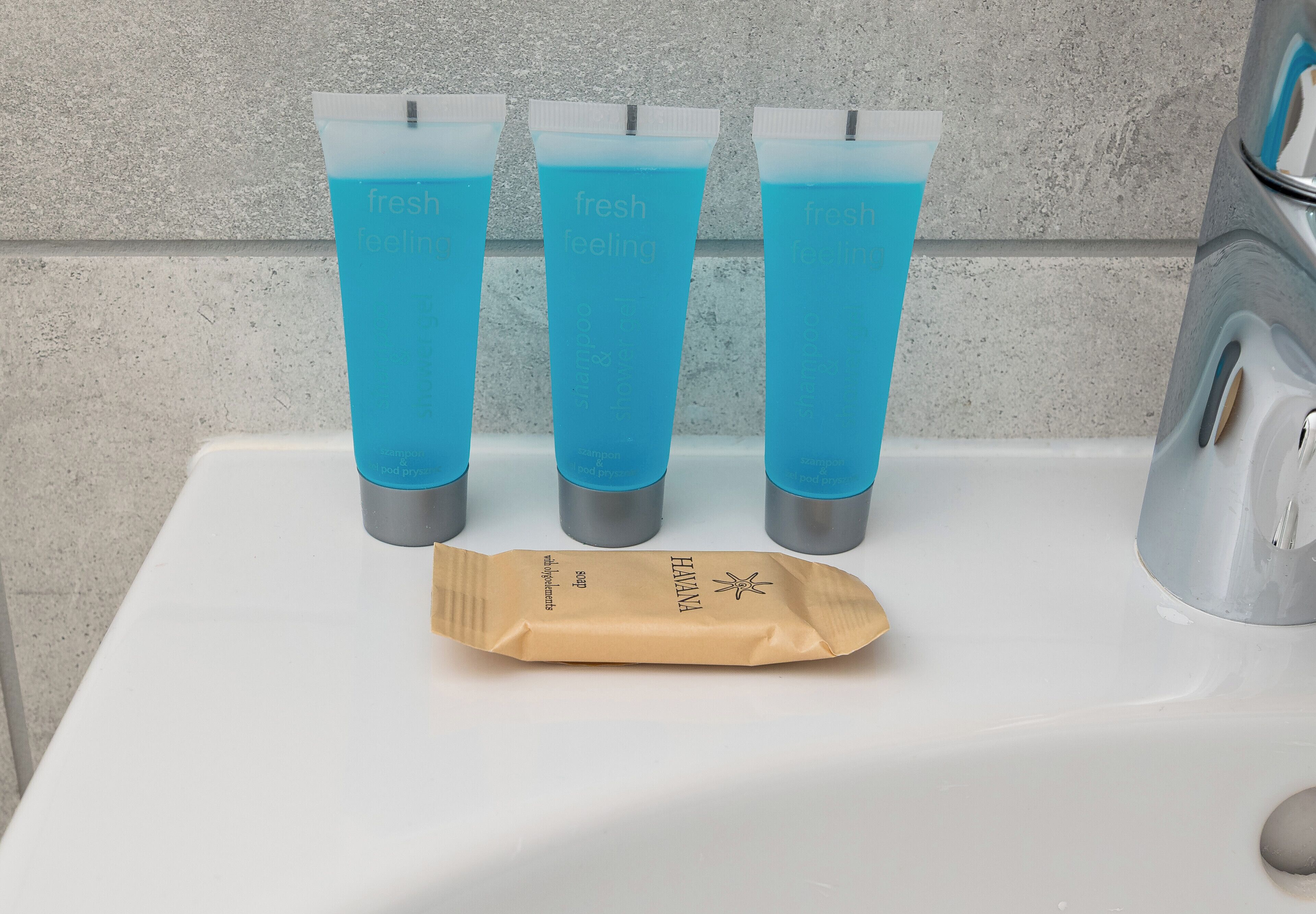 Trois tubes contenant un liquide bleu sont posés sur un lavabo blanc, à côté d’un robinet.