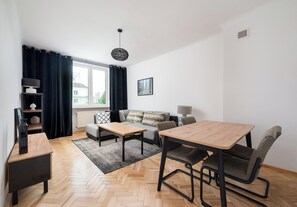 A modern living room with a sofa, a dining table, and a coffee table. - Metro Racławicka Exclusive Apartment (Warszawa)