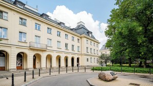 A building with multiple windows, a paved courtyard, and a large tree. - Warecka City Center Living Apartment (Warszawa)