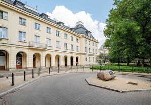 A building with multiple windows, a paved courtyard, and a large tree. - Warecka City Center Living Apartment (Warszawa)