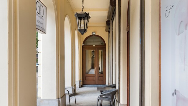 A corridor with a wooden door at the end, a hanging lantern, and a bench. - Warecka City Center Living Apartment (Warszawa)