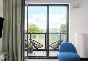 Een kamer met een grote glazen schuifdeur die leidt naar een balkon met twee stoelen en een potplant.
