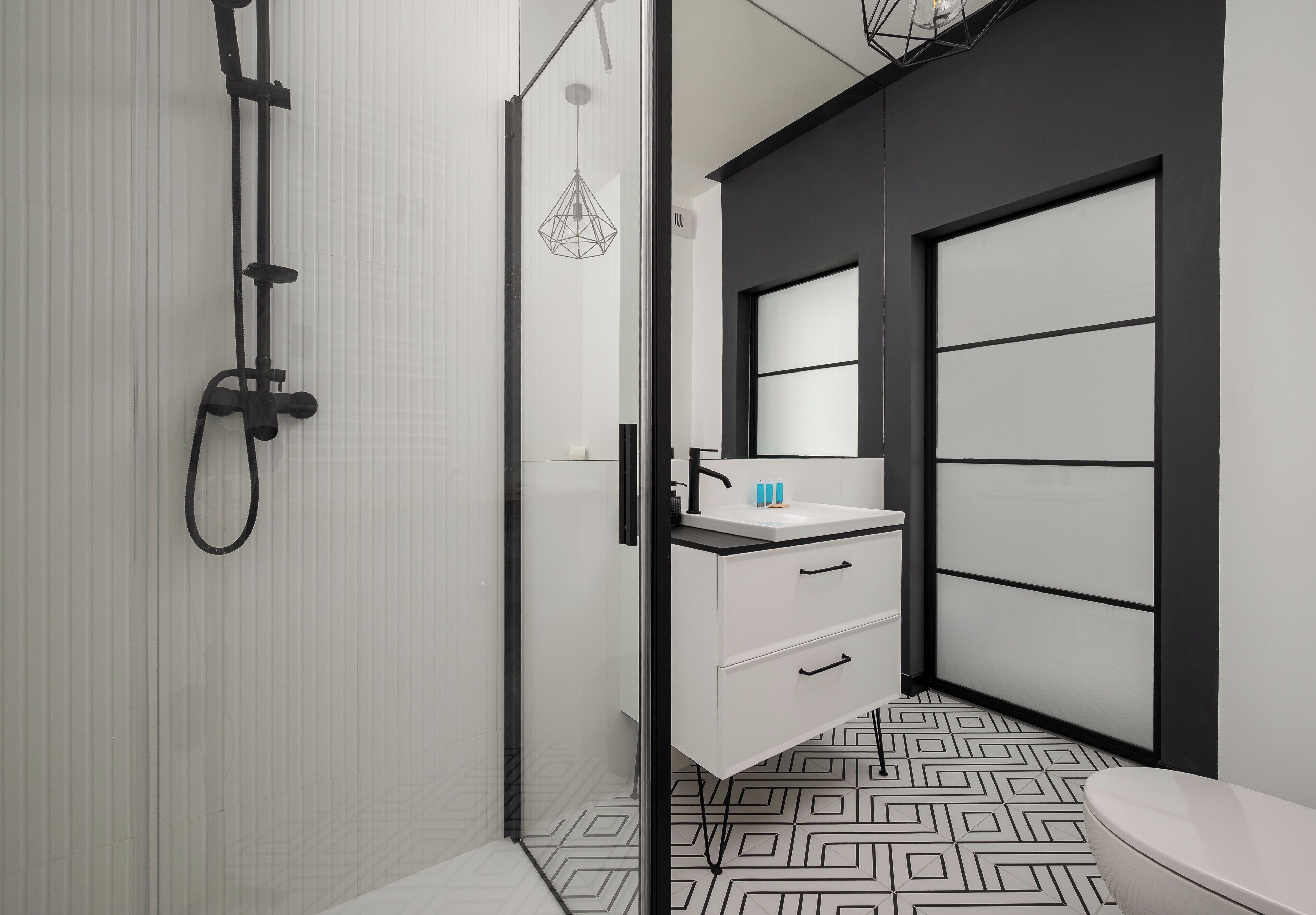 A modern bathroom with a shower, a sink with a mirror, and a toilet.