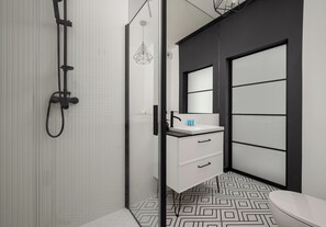 Ein modernes Badezimmer mit Dusche, Waschbecken mit Spiegel und Toilette.