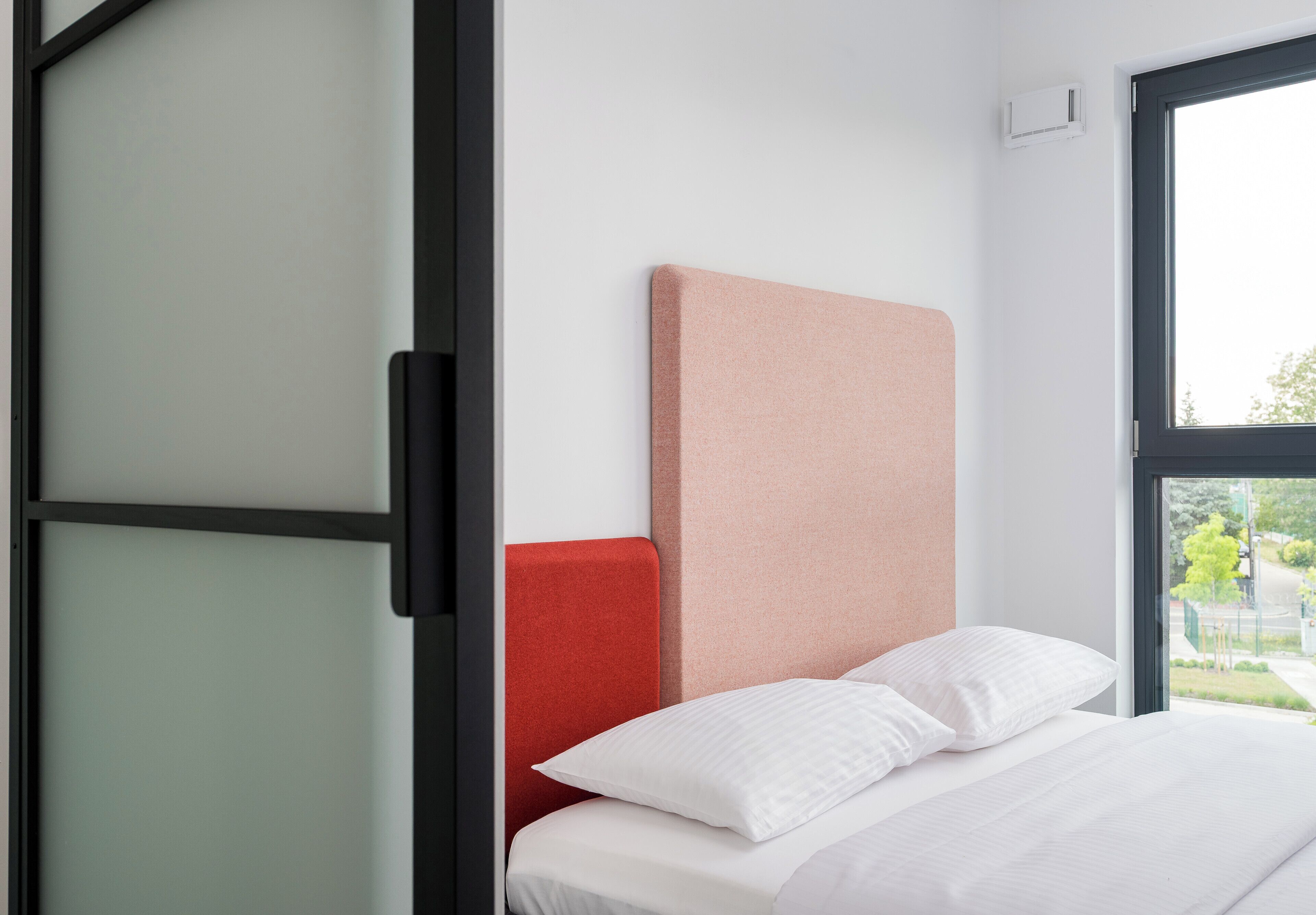 A bedroom with a bed, a window, and a sliding door.