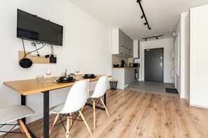 Eine moderne Küche mit einem Holztisch, weißen Stühlen, einem Flachbildfernseher und einem Essbereich.