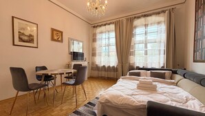 Une chambre d’hôtel comprenant un lit, un bureau avec des chaises, une télévision et un lustre.