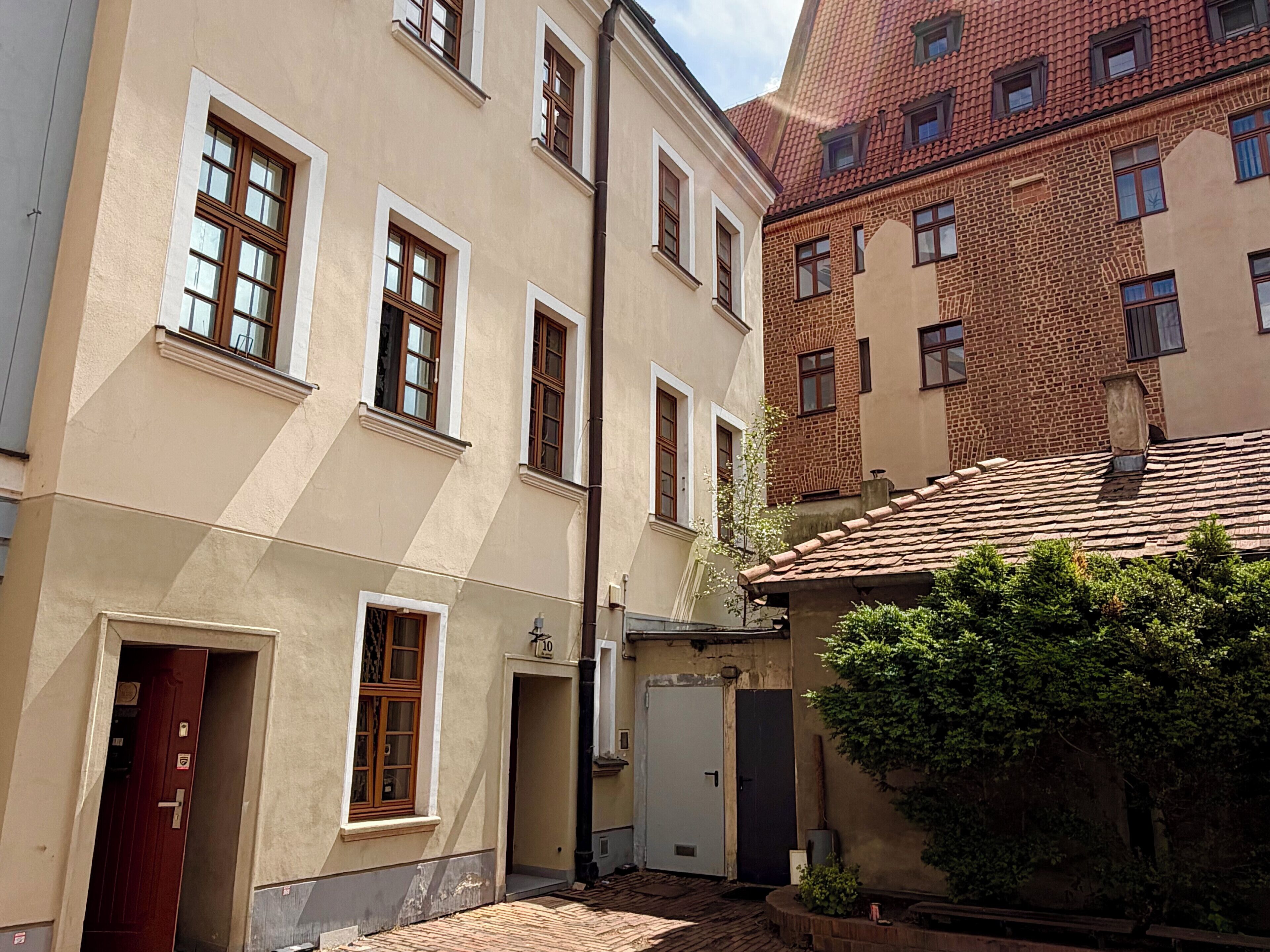 Eine schmale Straße mit Gebäuden im traditionellen Stil, darunter eine Ziegel-Fassade und ein cremefarbenes Gebäude mit zahlreichen Fenstern.