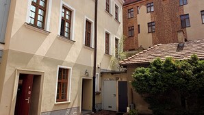 Une rue étroite bordée d’immeubles à l’architecture traditionnelle, notamment une façade en briques et un bâtiment de couleur crème doté de nombreuses fenêtres.