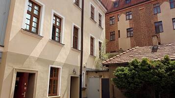 Eine schmale Straße mit Gebäuden im traditionellen Stil, darunter eine Ziegel-Fassade und ein cremefarbenes Gebäude mit zahlreichen Fenstern.