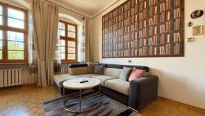 Un salon comprenant un canapé, une table basse, une bibliothèque et un radiateur.