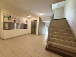 A hallway with a metal filing cabinet, an elevator, and a staircase. - Zakładowa Modern Living Studio (Wrocław)