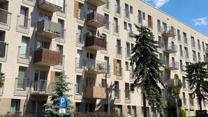 Un immeuble résidentiel à plusieurs étages, doté de balcons, d’un panneau indiquant un espace de stationnement et surplombant un ciel dégagé.