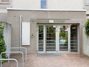A building entrance with a glass door, a metal handrail, and a sign indicating the entrance. - Zakładowa Modern Living Studio (Wrocław)