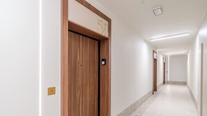 Un couloir avec une porte en bois portant le numéro « 58 » et un interrupteur sur le mur.