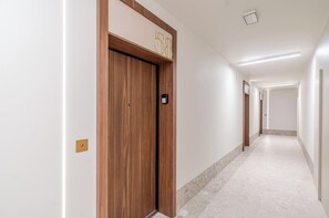 Un couloir avec une porte en bois portant le numéro « 58 » et un interrupteur sur le mur.