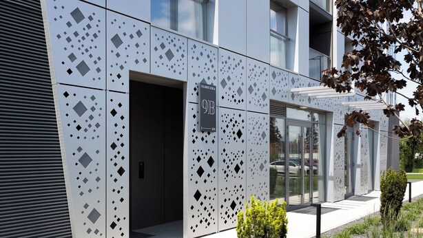 Une façade moderne ornée de motifs géométriques, une entrée bien visible et une enseigne indiquant l’adresse.